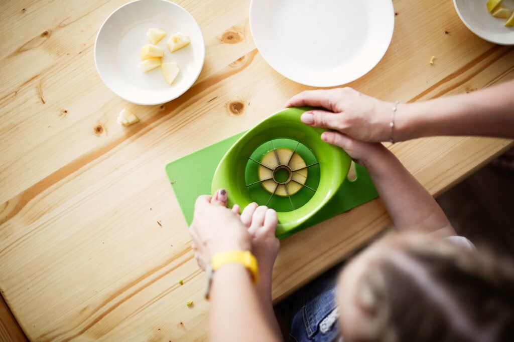 imagen de un niño cortando una manzana mientras practica Montessori en casa.