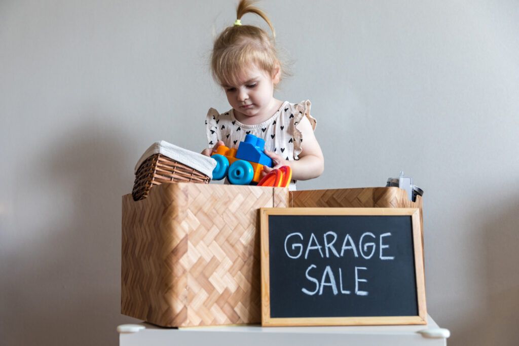 foto de un niño mirando a través de una caja de venta de garaje en busca de juguetes montessori baratos.
