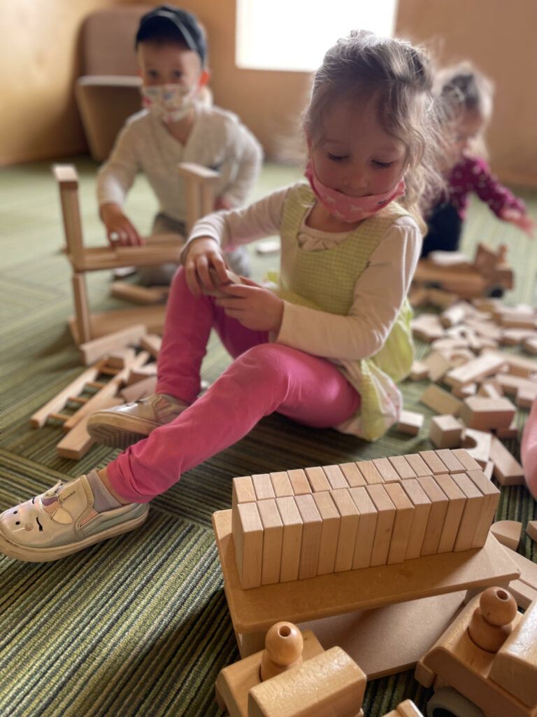 niños pequeños que demuestran el juego asociativo mientras construyen con bloques de madera.